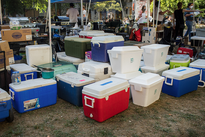 A growing pile of mismatched coolers sits next to the cooking tent.