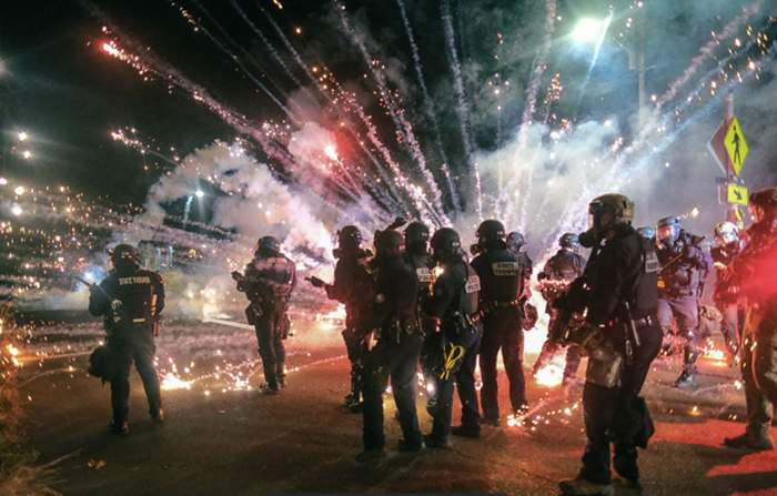 Fireworks explode as police attempt to stop protesters from marching on Stark Street near 113th Avenue.