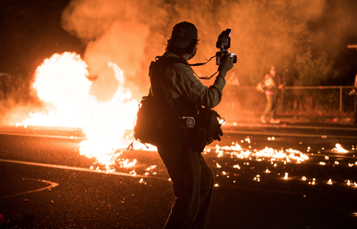 A member of the press photographs the action.