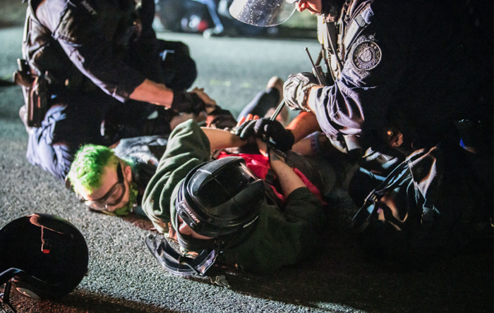 Oregon State Troopers, called in by Gov. Brown to assist police, arresting protesters.