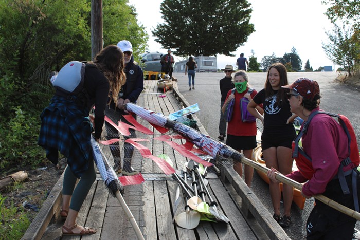 A group of people roll up a banner on a dock