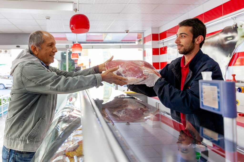 A man purchases meat from the meat market of an ethnic grocery store. 